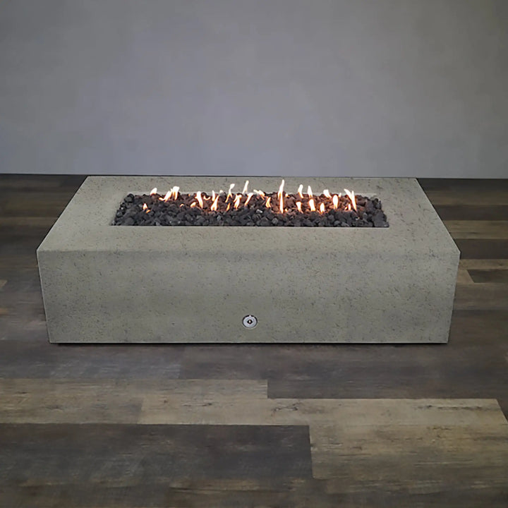 Wide view of the Starfire Designs Concrete Rustic 72" x 38" Rectangle Gravity Gas Fire Pit in Beige, placed in an indoor-like setting with a wooden floor. The image highlights the fire pit's large, rectangular design and its versatility for both indoor display and outdoor use in protected areas