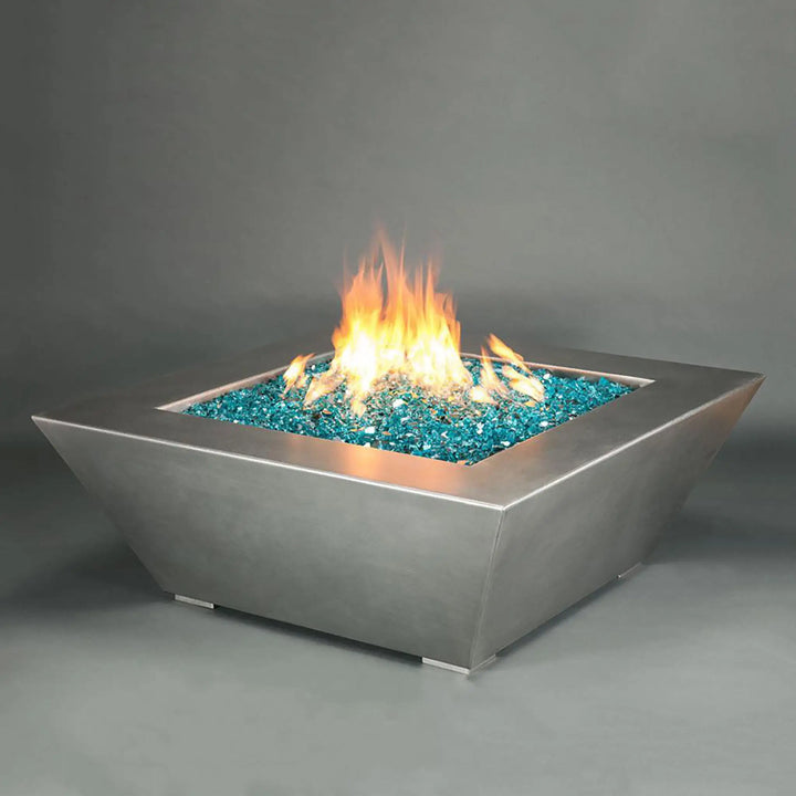 The Starfire Designs Edge Stainless Steel Gas Fire Pit in 48 inches, featuring an elegant angular design with a contemporary stainless steel finish, filled with vibrant blue fire glass, producing a striking flame display, perfect for modern outdoor settings. This luxury fire pit provides both style and warmth, ideal for patios and backyards