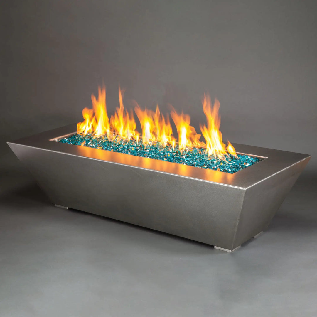 A large 72x40 inch Starfire Designs Edge Stainless Steel Gas Fire Pit, showcasing a sleek and robust stainless steel structure with an expansive bed of blue fire glass. The vivid flames create a captivating display, making this fire pit an ideal centerpiece for expansive outdoor spaces, providing warmth and modern elegance