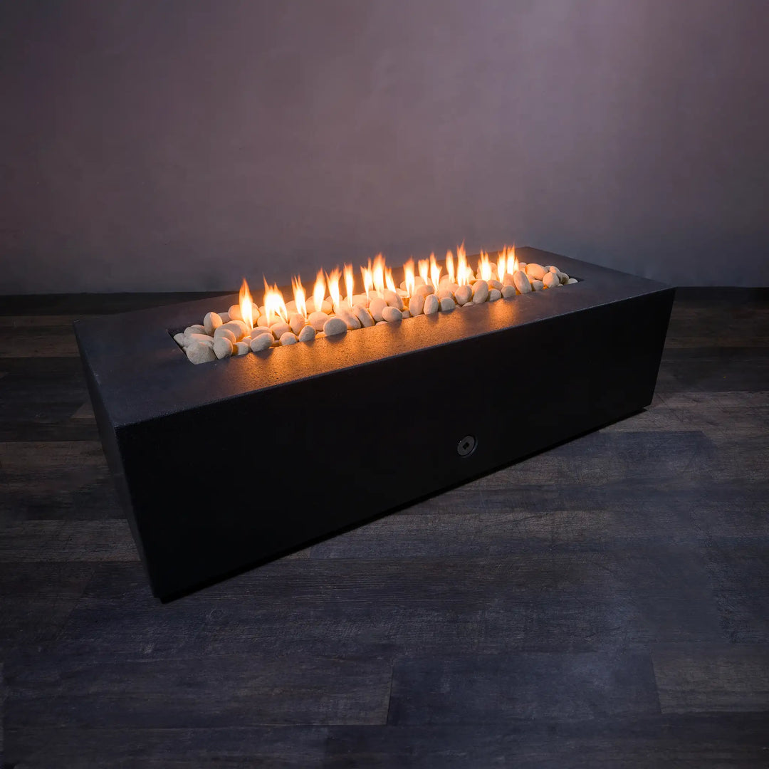 A rectangular fire pit filled with beige fire pebbles, with flames rising between the stones, creating a warm and inviting outdoor atmosphere. The beige fire pebbles add a natural and modern aesthetic to the fire feature, perfectly complementing the sleek black design of the fire pit. Ideal for modern outdoor spaces, these fire pebbles are durable and resistant to heat