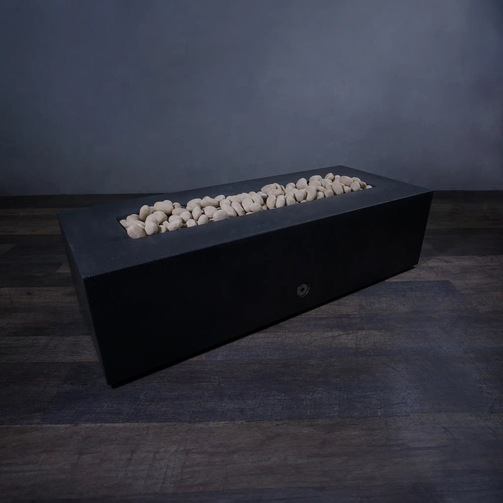 A modern rectangular fire pit filled with beige fire pebbles, without flames, showcasing the natural texture and smooth surface of the fire-resistant ceramic pebbles. The fire pit provides a clean, minimalistic look, perfect for contemporary outdoor settings. These fire pebbles are ideal for enhancing the aesthetic of any fire feature