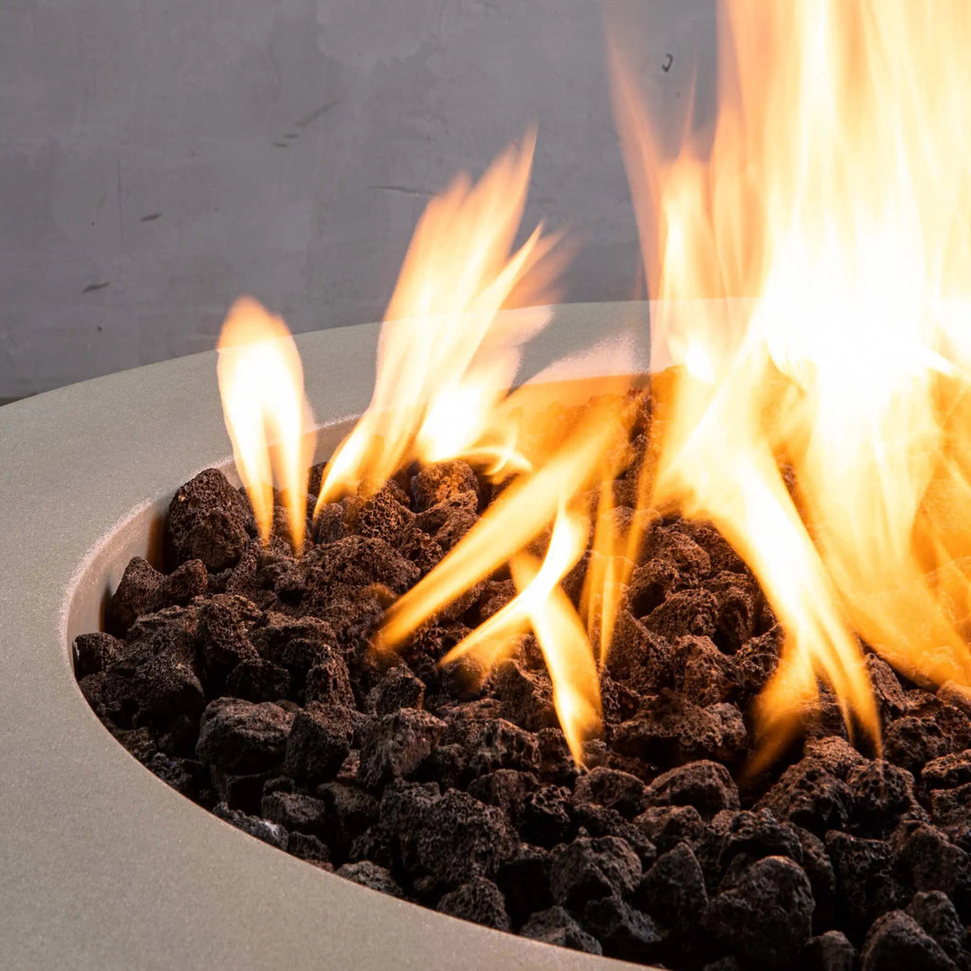 Close-up of the Starfire Designs Gravity 36-inch round concrete gas fire pit in beige with natural lava rocks and an intense flame, highlighting its premium finish and fire aesthetics, suitable for residential or commercial use