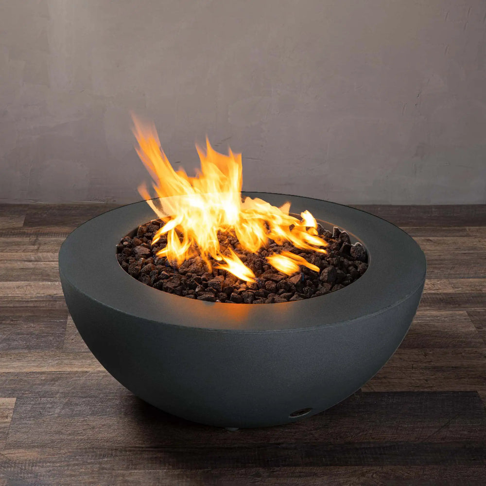 Side angle view of Starfire Designs Gravity 36-inch Round Concrete Gas Fire Pit in Graphite with blazing flames, showcasing the smooth, round structure and premium weather-resistant concrete. Designed for natural gas or propane, this fire pit offers an elegant outdoor heating solution