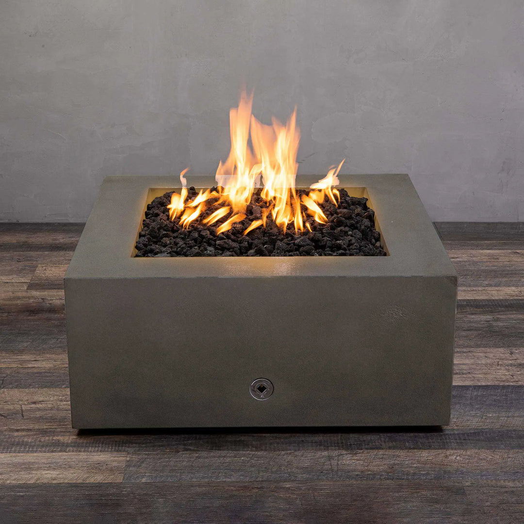 Starfire Designs Gravity 36-inch square concrete gas fire pit in brown with bright flames rising from black lava rocks. Modern outdoor fire pit made from durable concrete for residential and commercial use. Perfect for patios and backyards, this luxury fire pit adds warmth and ambiance. High-quality fire pit with stainless steel burner and propane/natural gas compatibility