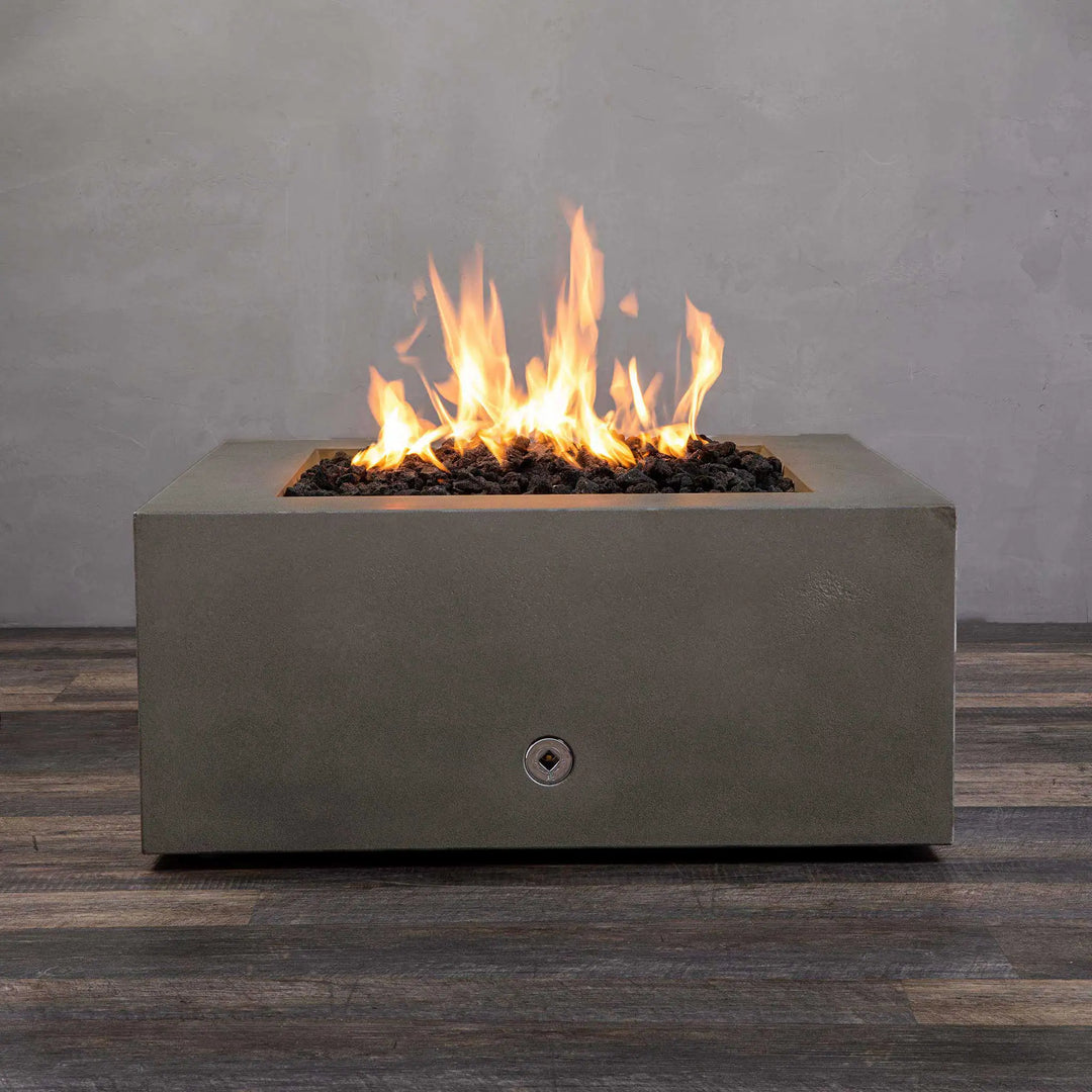 Starfire Designs Gravity 36-inch square concrete gas fire pit in brown with bright flames rising from black lava rocks. Modern outdoor fire pit made from durable concrete for residential and commercial use. Perfect for patios and backyards, this luxury fire pit adds warmth and ambiance. High-quality fire pit with stainless steel burner and propane/natural gas compatibility