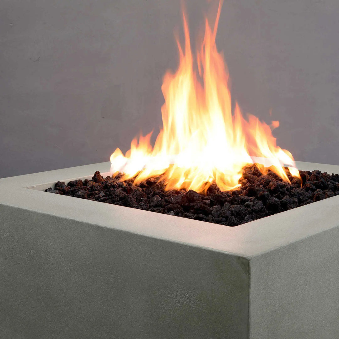 Close-up of the Starfire Designs Gravity 36-inch Square Concrete Gas Fire Pit flame, set against natural gray concrete. The clean, elegant flame rises through black lava rocks, creating a striking visual for outdoor spaces, ideal for both residential and commercial settings