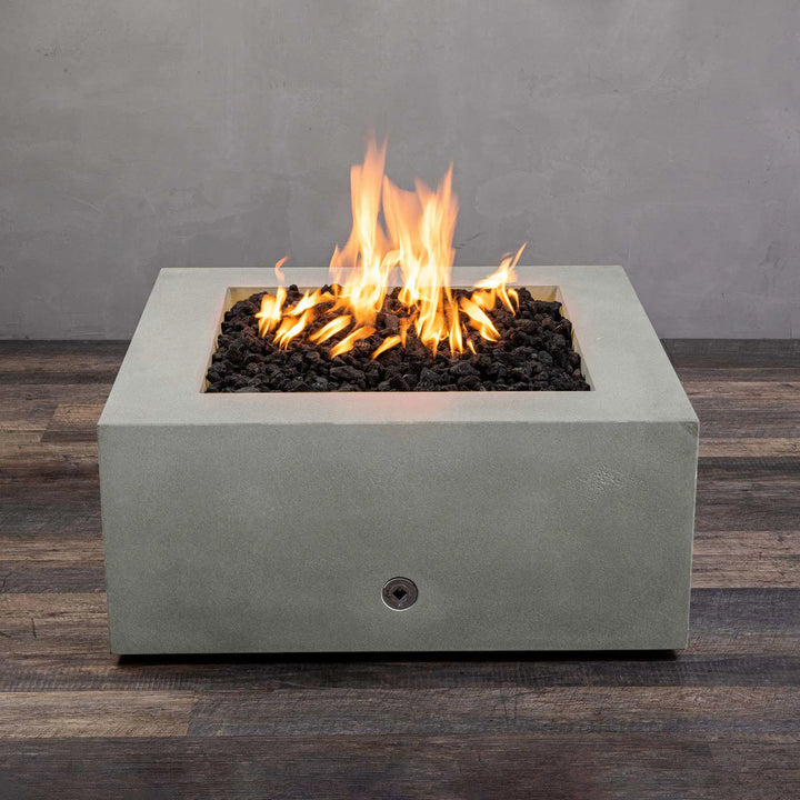 Top view of the Starfire Designs Gravity 36-inch Square Concrete Gas Fire Pit in natural gray finish, featuring a central flame surrounded by lava rocks. This outdoor gas fire pit adds a modern touch with its smooth, square design and is perfect for enhancing any patio or landscape project