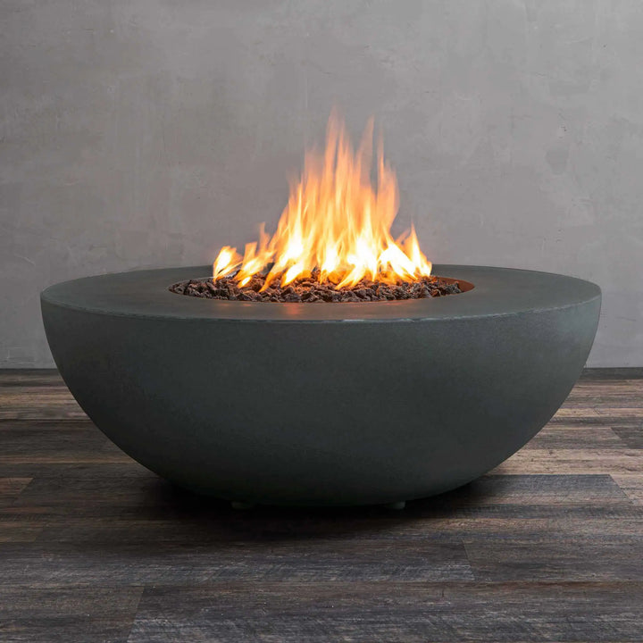 Starfire Designs Gravity 45-inch Round Concrete Gas Fire Pit in Graphite finish, featuring a warm flame with lava rocks. This luxury fire pit has a sleek, modern look, perfect for outdoor living spaces. The fire pit is weather-resistant and built with high-end concrete material, ideal for residential or commercial use. Graphite concrete fire pit, outdoor fire feature, luxury gas fire pit, durable concrete design.