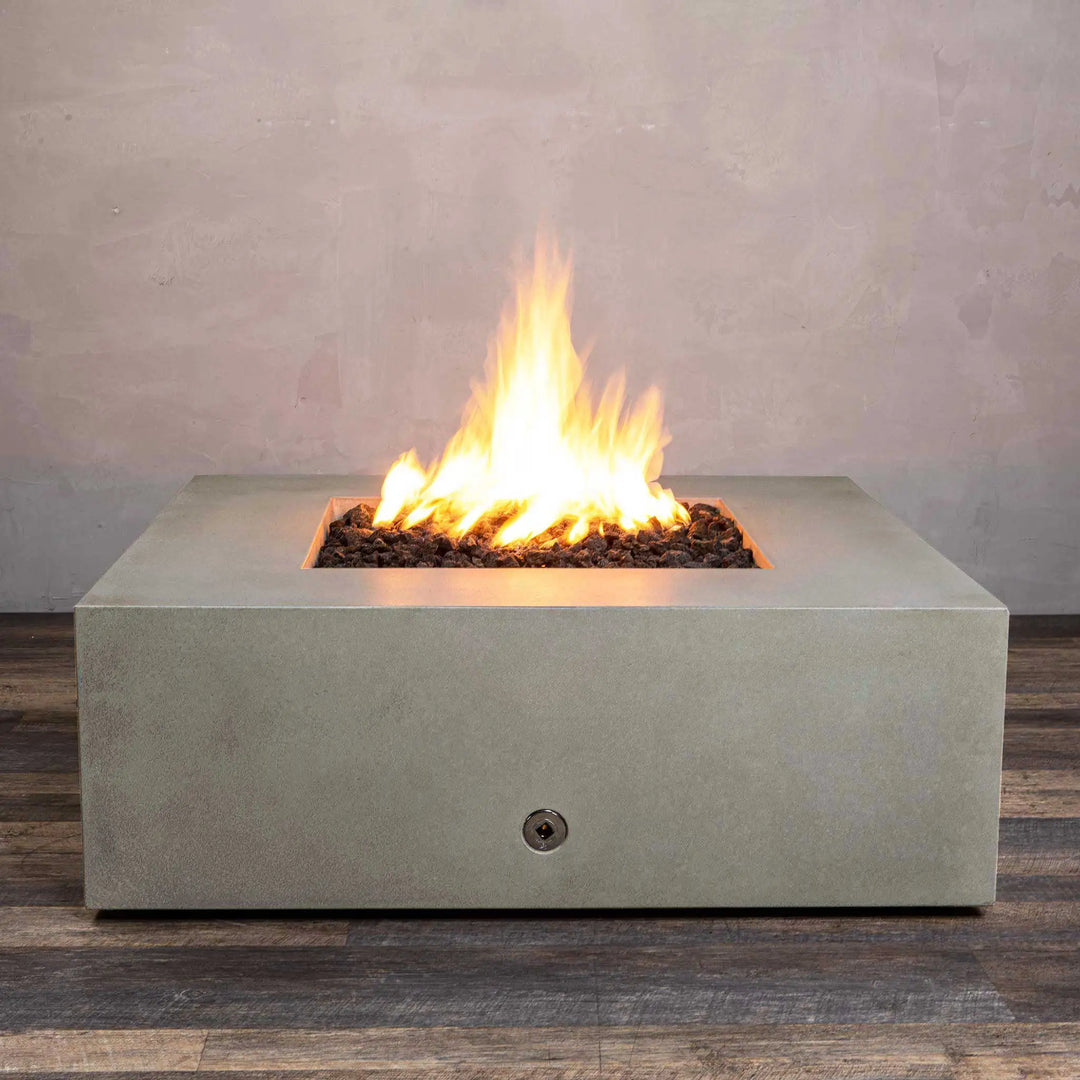 A glowing Starfire Designs Gravity 45" Square Concrete Gas Fire Pit in beige, showing a robust flame surrounded by lava rocks. This fire pit is crafted from high-quality concrete and designed for modern outdoor spaces, blending seamlessly into natural surroundings with its neutral beige color. Ideal for warmth and ambiance.