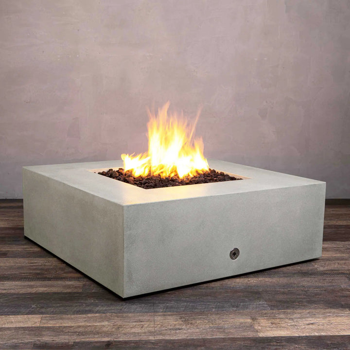 Angled view of the Starfire Designs Gravity 45-inch Square Concrete Gas Fire Pit in natural gray with glowing flame and lava rocks. High-quality concrete construction provides both durability and contemporary aesthetics, ideal for luxury outdoor settings