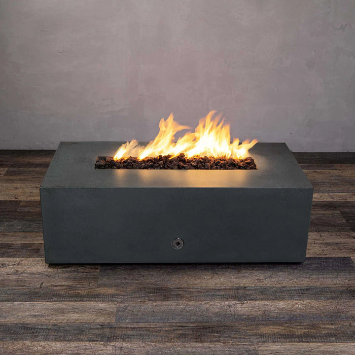 Graphite Starfire Designs Gravity 48" x 32" rectangle gas fire pit, showcasing bright, dancing flames above dark lava rocks. The fire pit's sturdy concrete structure, weather-resistant surface, and refined modern appearance create an elegant outdoor heating solution for patios and decks