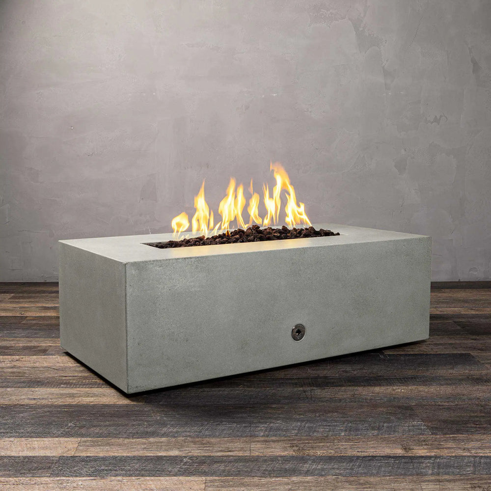 A side-angle view of the Starfire Designs Gravity 48" x 32" rectangle concrete gas fire pit in natural gray, showing its sleek concrete structure with a glowing flame. Designed for outdoor living spaces, this fire pit adds a modern touch with its durable concrete body and adjustable flames. 