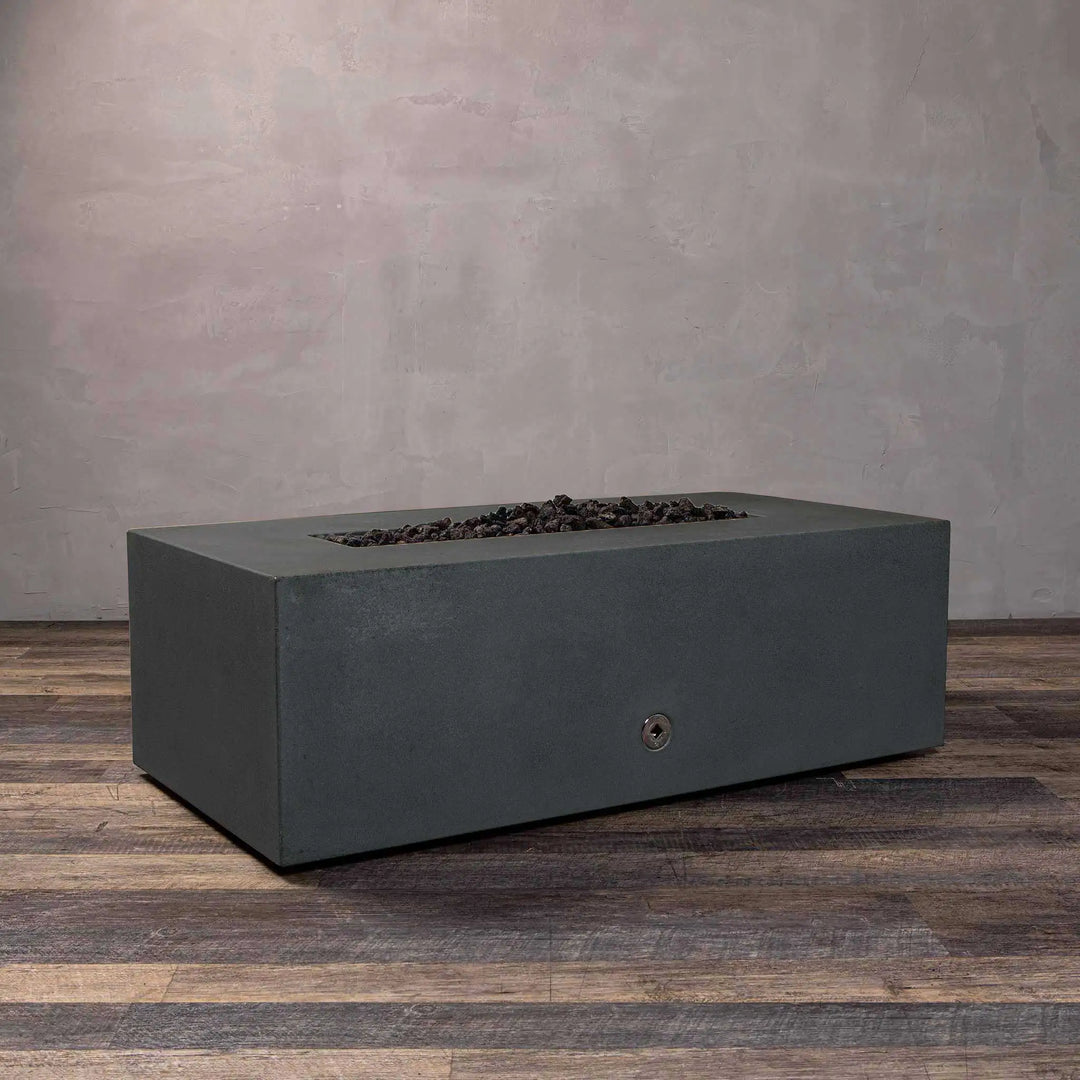 Angled view of the Starfire Designs Gravity 60" x 24" Linear Concrete Gas Fire Pit in Graphite with no flames, emphasizing the smooth surface and robust construction. Perfect for outdoor fire bowls and luxury fire pit areas in modern gardens