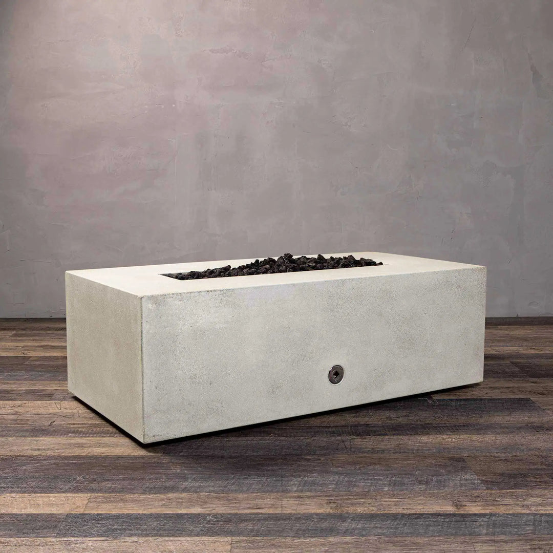 Angular view of Starfire Designs Gravity 60-inch by 24-inch linear concrete gas fire pit in white with black lava rocks, showcasing contemporary design for large backyard fire pits, outdoor gas fire pits, and modern luxury fire pits