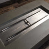 Detailed view of the burner system in the Starfire Designs Gravity 60" x 32" Rectangle Concrete Gas Fire Pit, showcasing the high-quality stainless steel components that provide a consistent flame.