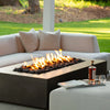 The Starfire Designs Gravity 60" x 32" Rectangle Concrete Gas Fire Pit in brown, surrounded by outdoor furniture, creating a warm and inviting patio space. Ideal for modern outdoor setups. 