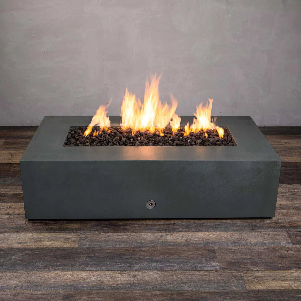 Front view of the Starfire Designs Gravity 60" x 32" Rectangle Gas Fire Pit in Graphite, with a full, even flame across the burner. This minimalist fire pit is crafted from durable concrete in a dark graphite finish. The rectangular design fits effortlessly into outdoor spaces, adding warmth and style to patios or decks. Graphite fire pit, modern patio fire feature, concrete gas fire pit.