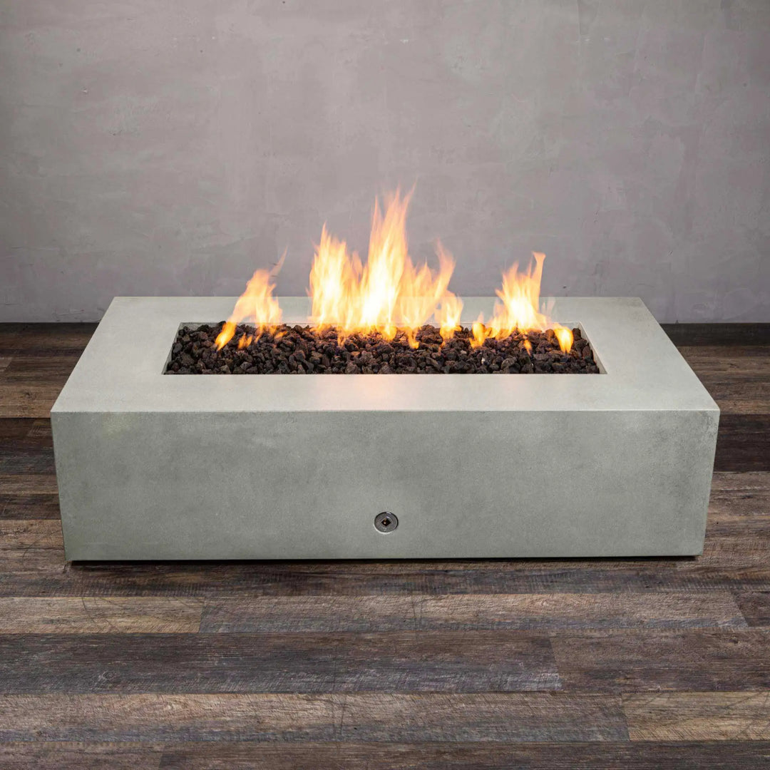 Front angle view of the Starfire Designs Gravity 60" x 32" rectangle concrete gas fire pit in natural gray, with a lively flame rising from the center. The fire pitâ€™s minimalist design with clean lines complements contemporary outdoor environments. The natural gray concrete finish adds a neutral yet striking visual appeal. Equipped with a premium gas burner system, it ensures long-lasting performance