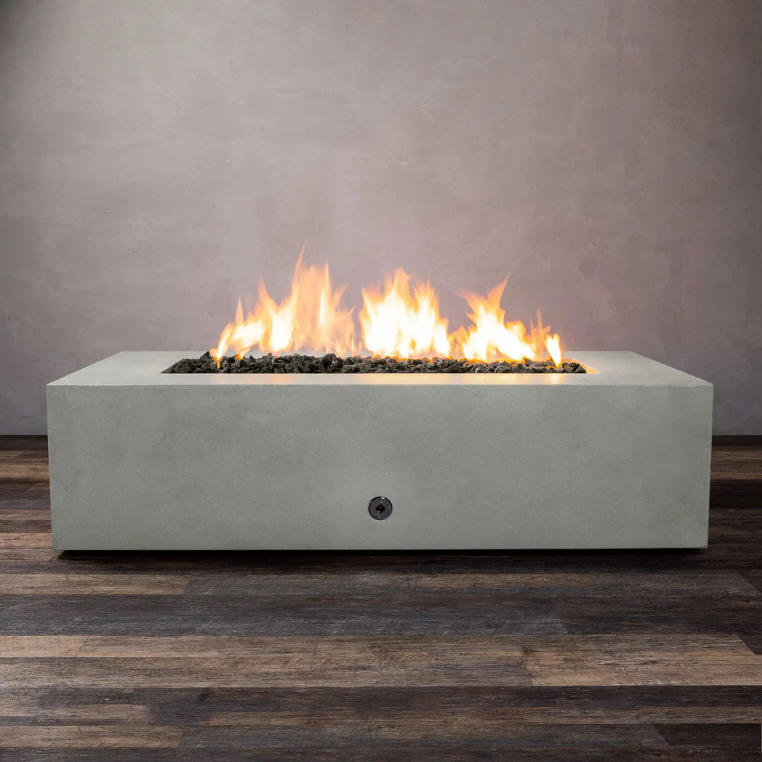 Starfire Designs Gravity 60" x 32" rectangle concrete gas fire pit in natural gray, showcasing a vibrant flame. This outdoor fire pit offers a sleek, modern rectangular shape with a smooth concrete finish, ideal for high-end outdoor spaces. It features a spacious burner area with black lava rock, providing a luxurious ambiance. Perfect for outdoor gatherings, patios, and entertainment areas.