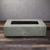 Starfire Designs Gravity 60" x 32" rectangle concrete gas fire pit in natural gray without flames. The smooth, sleek surface highlights the quality of the concrete construction. Lava rocks fill the burner area, providing a rustic contrast to the modern design. Ideal for upscale outdoor spaces like patios, gardens, and pool areas, offering both aesthetic beauty and functionality.