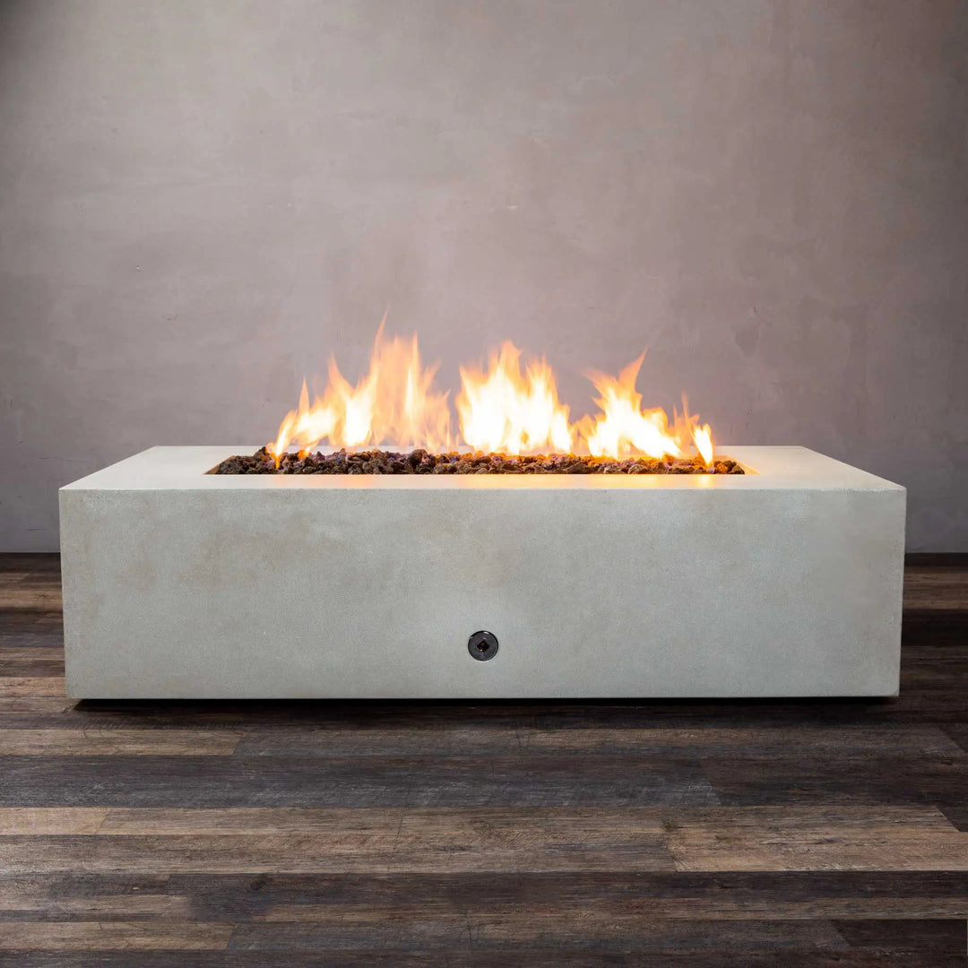 A front view of the Starfire Designs Gravity 60" x 32" Rectangle Concrete Gas Fire Pit in white with an active flame. This luxurious fire pit features a sleek rectangular design made from durable concrete, providing a modern aesthetic to any outdoor space. Perfect for backyard gatherings or commercial settings, this gas fire pit offers both style and functionality.