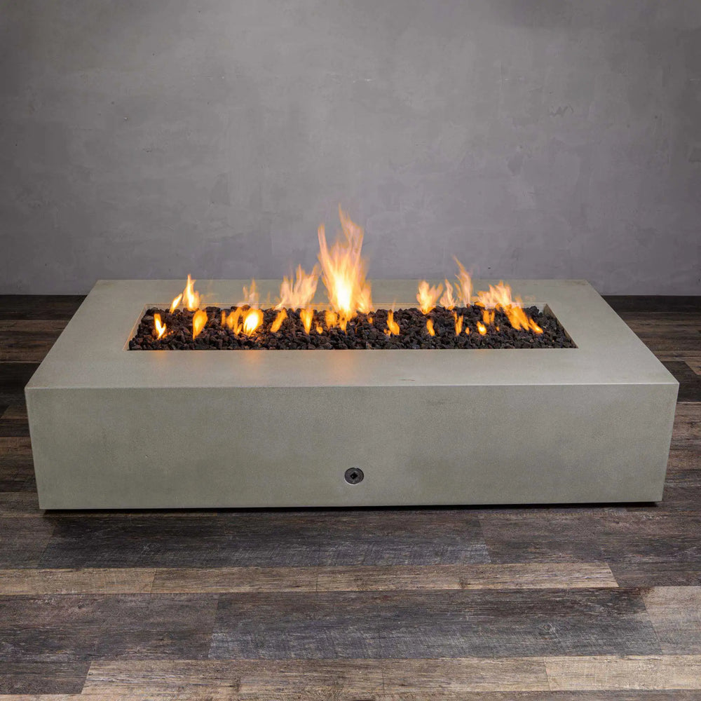 Front view of the Starfire Designs Gravity 72-inch x 38-inch rectangular beige concrete gas fire pit with a vibrant flame. This luxurious fire pit offers a spacious burning area filled with lava rocks, enhancing the visual appeal and delivering warmth for outdoor gatherings