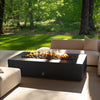 Starfire Designs Gravity 72-inch by 38-inch graphite concrete gas fire pit in a luxurious outdoor patio setting, surrounded by modern furniture. The warm, vibrant flames and sleek, contemporary design make this fire pit the perfect centerpiece for outdoor entertaining spaces. Its durable, weather-resistant construction ensures long-lasting performance.