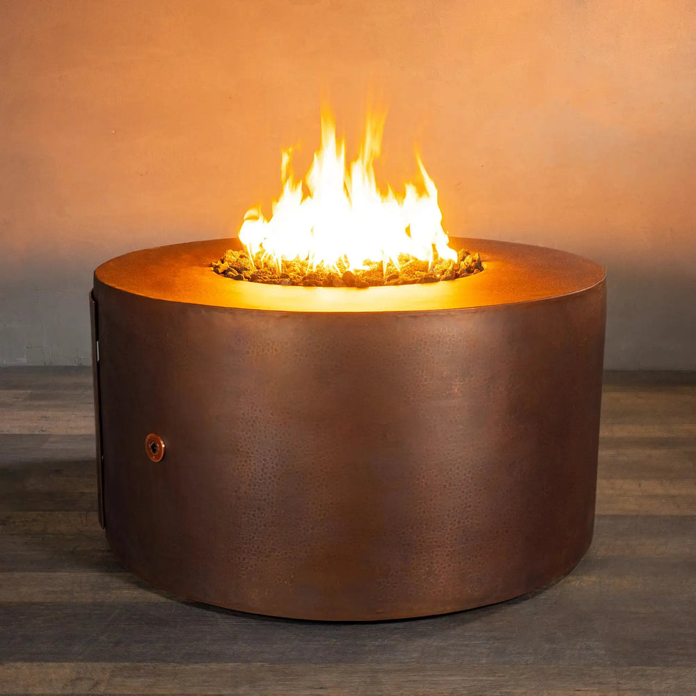 Lit view of the Gravity Moreno 45-inch round copper fire pit by Starfire Designs, highlighting the warm, inviting flames and the rich hammered copper texture, perfect for enhancing outdoor gatherings