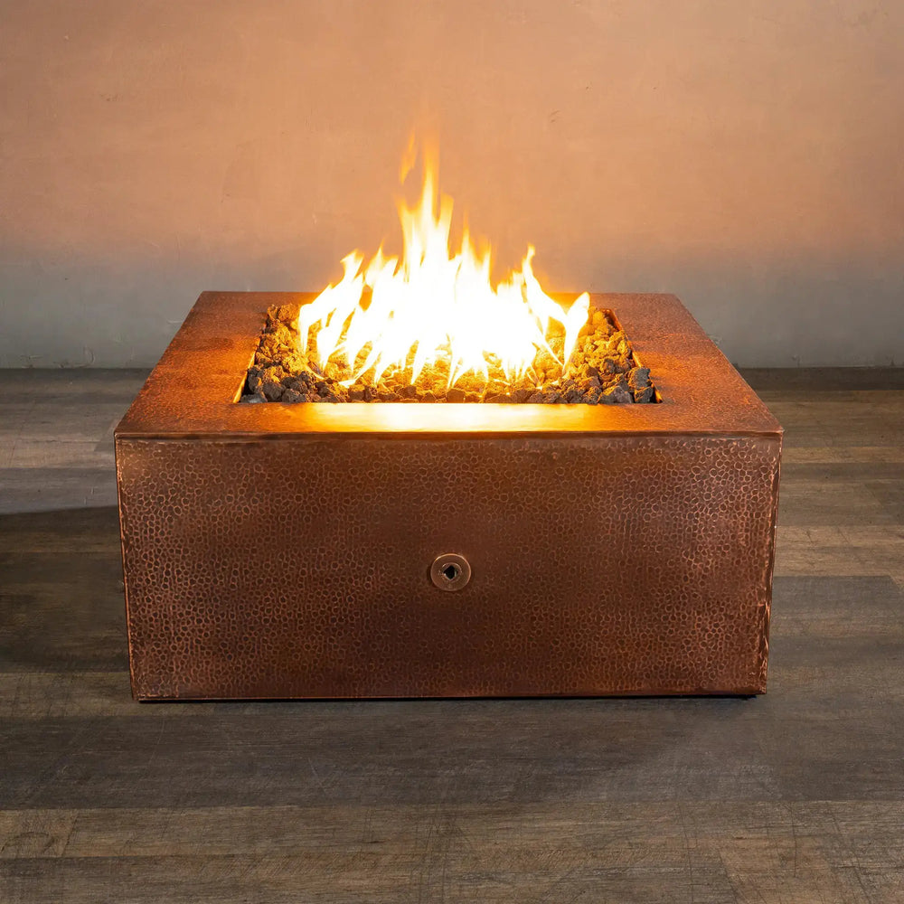 Front view of the Starfire Designs Moreno 36-inch square copper fire pit, lit with a vibrant flame, highlighting the hammered copper texture and creating a warm ambiance for outdoor spaces