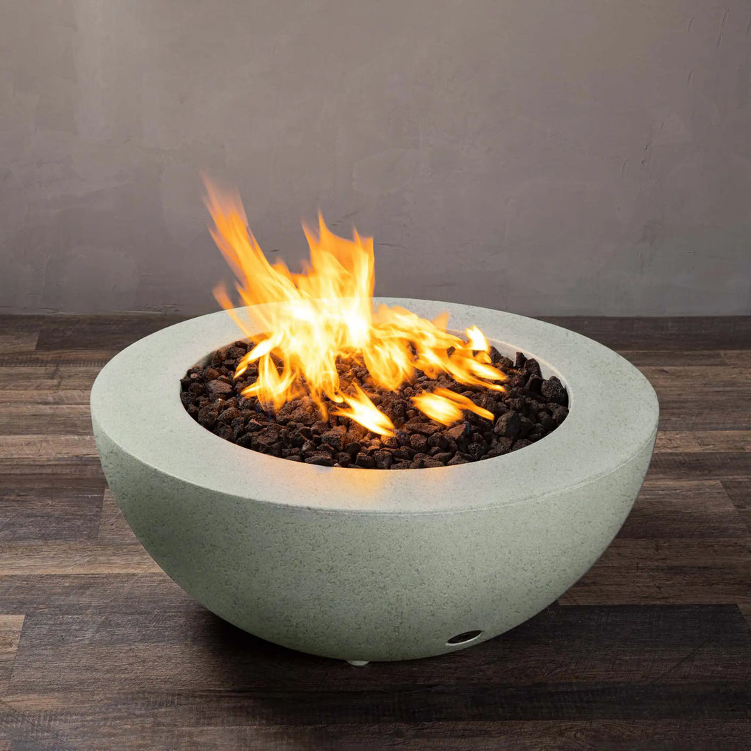 Side view of the Starfire Designs Rustic 36-inch Round Concrete Gravity Gas Fire Pit in Natural Gray with flames, showing the smooth concrete finish