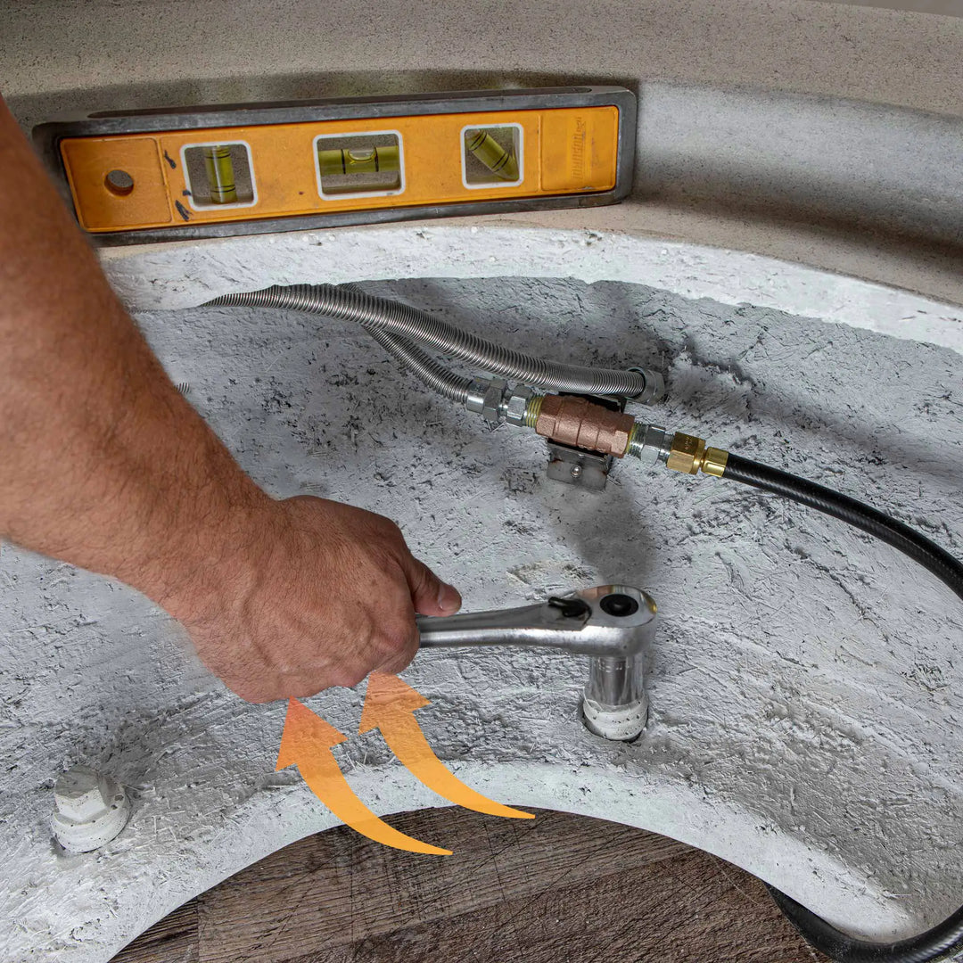 A hand connecting the gas line to the Starfire Designs Rustic 36-inch Round Concrete Gravity Gas Fire Pit in white, demonstrating the ease of installation and setup