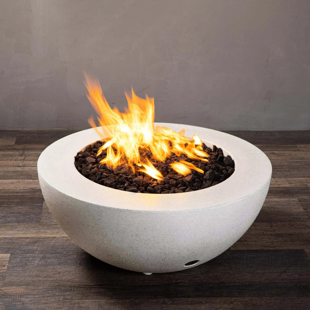 Side view of the Starfire Designs Rustic 36-inch Round Concrete Gravity Gas Fire Pit in white, showcasing the robust construction and even flames on a wooden surface