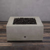 Top view of the empty fire pit bowl in the Starfire Designs Rustic Gravity 36-inch Square Concrete Gas Fire Pit in beige, without the flame, showing the concrete finish and lava rocks