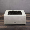 Full view of the Starfire Designs Rustic Gravity 36-inch Square Concrete Gas Fire Pit in White, featuring its modern aesthetic and spacious top with black lava rocks