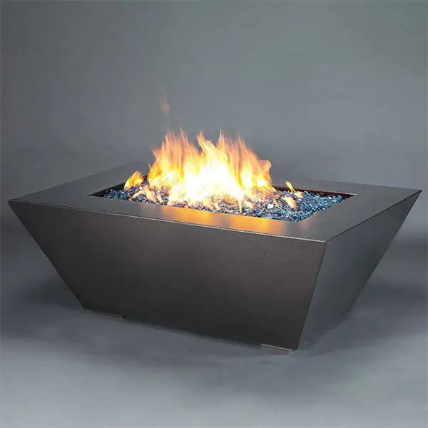 Full view of the Starfire Designs Steel Mill 60" x 32" Rectangle Gas Fire Pit in the Silver Hammertone finish. This fire pit is elegantly designed with a rectangular structure and a reflective, hammered silver surface, complete with a bright blue fire glass that enhances the flames. Ideal for outdoor use in luxurious residential or commercial spaces.