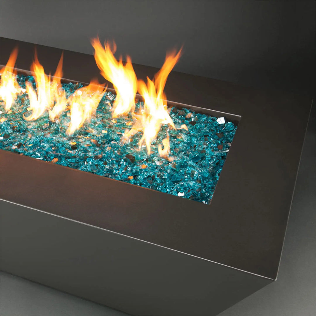 A modern rectangular outdoor fire pit filled with Starfire Glass 1/2" Broken Fire Glass (10lbs) in Pacific Blue Reflective, producing a dazzling flame effect. The high-quality reflective fire glass enhances brightness and durability, making it a perfect addition to a backyard fire table, patio fire pit, or gas fire bowl. Heat-resistant and eco-friendly, this fire glass provides a stylish upgrade.