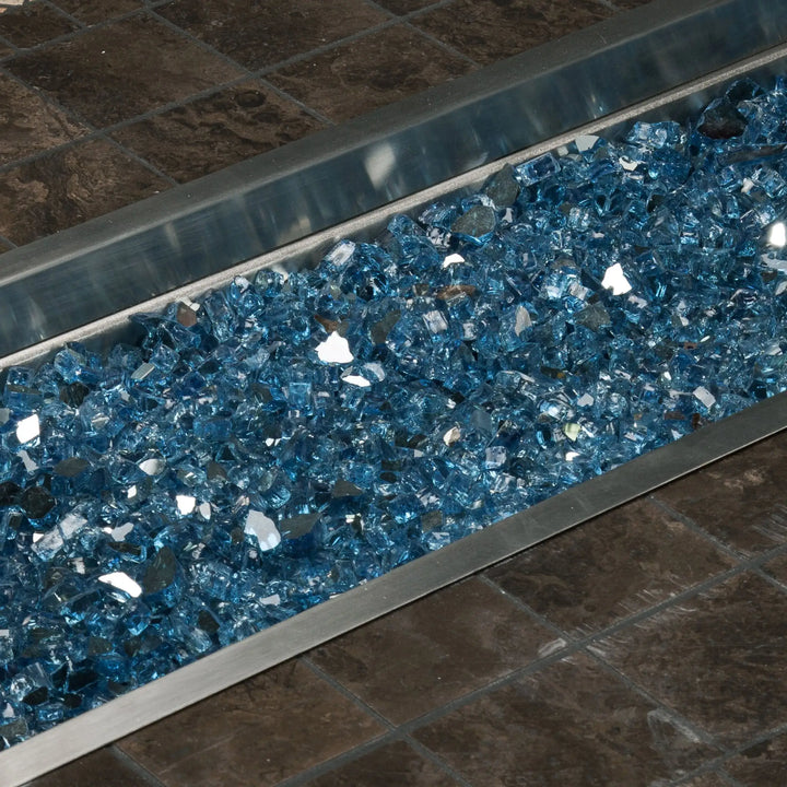 A close-up of Starfire Glass 1/2" Broken Fire Glass (10lbs) in Pacific Blue Reflective showcased in a stainless steel fire pit tray. The brilliant blue reflective glass intensifies the fire’s glow, creating a captivating effect. Perfect for modern gas fire pits, linear fire tables, and outdoor fireplaces, this durable fire glass ensures long-lasting performance and a stunning display.
