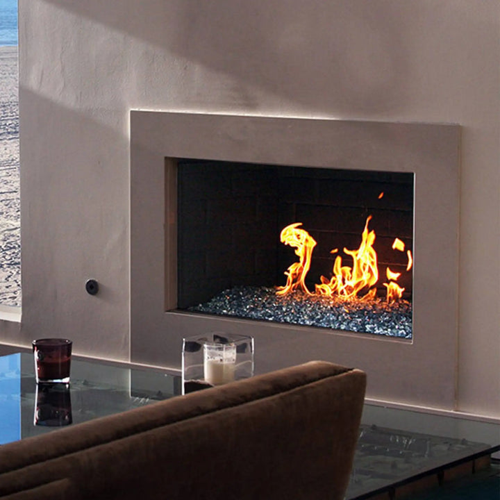 A sleek, built-in modern indoor gas fireplace featuring Starfire Glass 1/2" Broken Pre-Mixed Fire Glass (10lbs). The blue-toned reflective fire glass shimmers under the dancing flames, adding elegance to the contemporary living room. Ideal for fireplace inserts, natural gas fireplaces, and high-end fire pits.