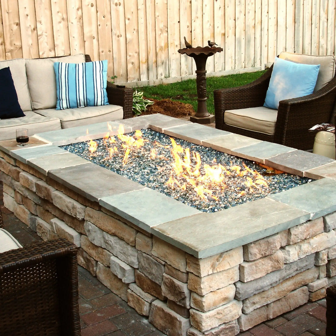 A modern built-in gas fireplace featuring Starfire Glass 1/4" Broken Pre-Mixed Fire Glass (10lbs) in blue and clear hues, offering a sleek, contemporary look. The reflective fire glass enhances the dancing flames, creating a warm, inviting ambiance in a minimalist living space. Designed for indoor gas fireplaces, this premium fire pit glass is heat-resistant and long-lasting, making it a perfect choice for luxury gas fireplaces.