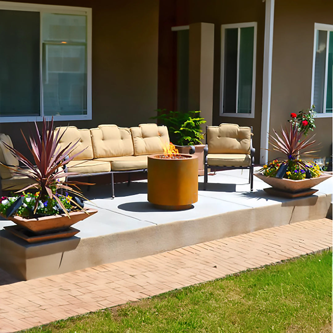 This image showcases the Outdoor Plus 30" Beverly Steel Gas Fire Pit on a modern patio setting. The fire pit is prominently featured in a corten steel finish, surrounded by beige cushioned patio furniture and decorative planters. The fire pit's sleek design enhances the outdoor space, creating a warm and inviting atmosphere.