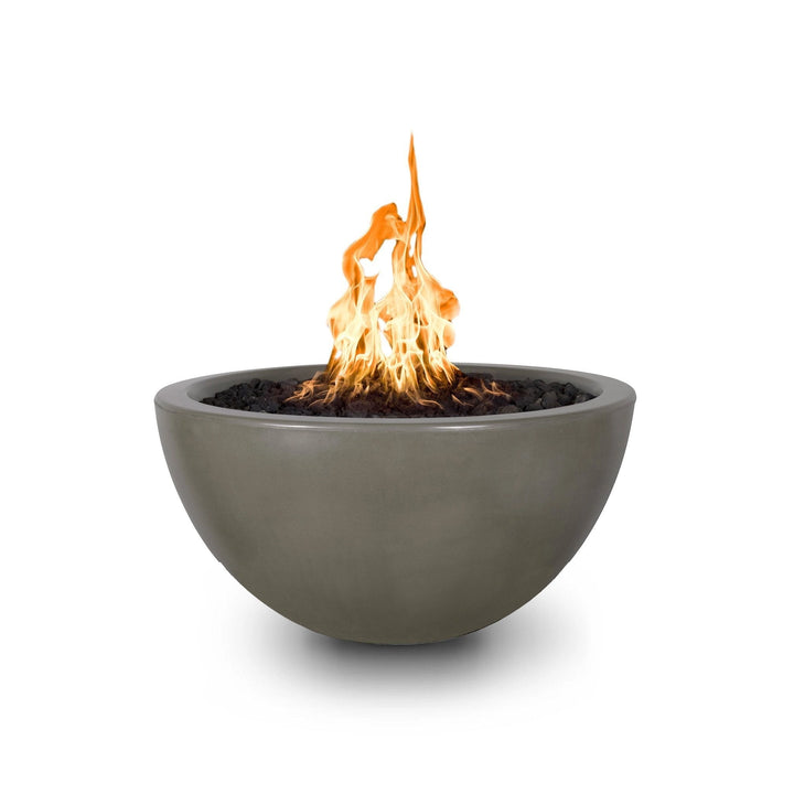 his image displays The Outdoor Plus 30" Luna Concrete Gas Fire Pit in the ash finish, with an active flame burning in the center. The fire pit's smooth, curved concrete design creates an elegant, minimalist aesthetic perfect for modern outdoor settings. The fire pit uses natural gas and features a dark-colored fire media that enhances the contrast with the ash-colored base. This fire pit is ideal for creating a warm, inviting ambiance in any backyard or patio space.