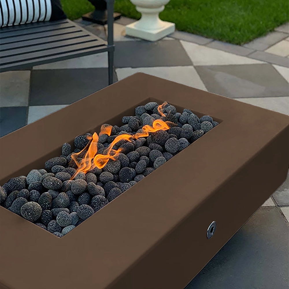 The Outdoor Plus 60-inch Del Mar Concrete Gas Fire Pit in a deep chocolate finish, creating a cozy outdoor atmosphere with its warm flame and dark lava rocks. Ideal for backyards and patios, this fire pit combines style and function for modern outdoor living.