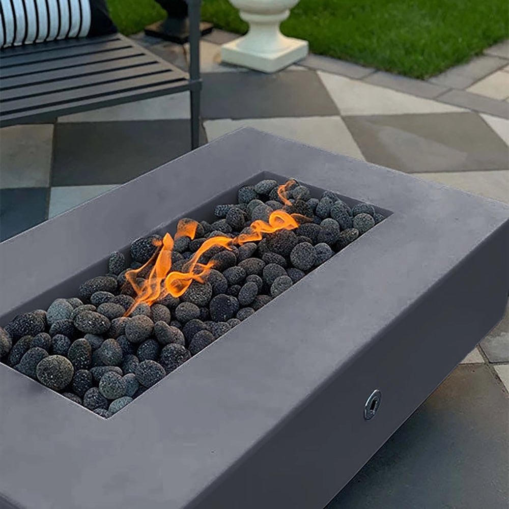 The Outdoor Plus 60-inch Del Mar Concrete Gas Fire Pit in a modern gray color, offering a sophisticated touch to outdoor spaces. This natural gas fire pit, with dark lava rocks and a controlled flame, is perfect for stylish backyards and patios.