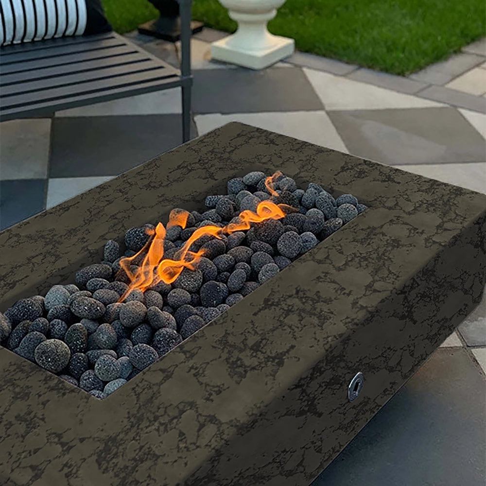 The Outdoor Plus 60-inch Del Mar Concrete Gas Fire Pit in moss stone finish showcasing a natural stone-like texture, ideal for outdoor settings. This fire pit combines durable construction with a refined design, creating a captivating flame display among dark lava rocks, perfect for any backyard or patio decor. Modern gas fire pit with luxury outdoor ambiance.