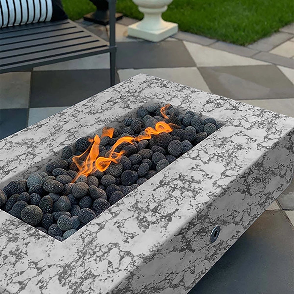 The Outdoor Plus 60-inch Del Mar Concrete Gas Fire Pit in rustic white with a marbled appearance, adding a touch of elegance to outdoor settings. This gas fire pit combines a sleek design with captivating flames over black lava stones, ideal for upscale patios or garden fire features. Luxury fire pit for modern outdoor decor.