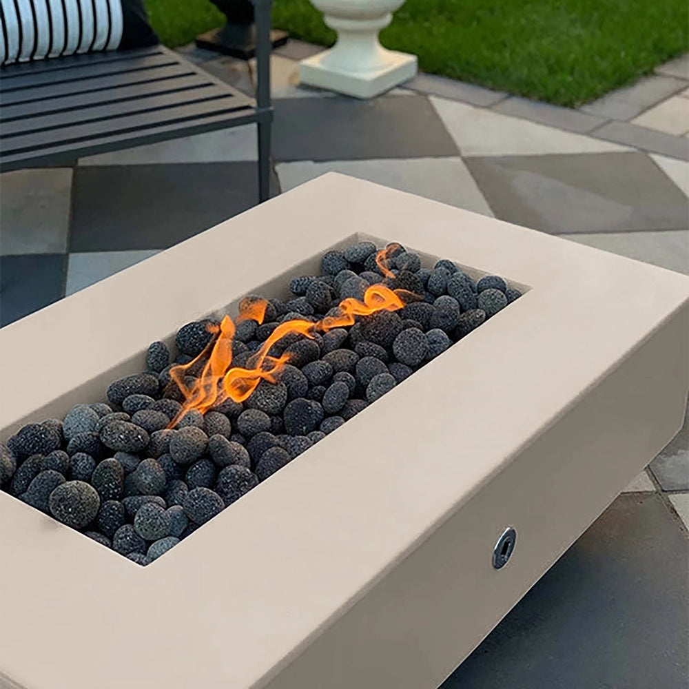 The Outdoor Plus 60-inch Del Mar Concrete Gas Fire Pit in vanilla, a soft neutral shade that blends seamlessly with various outdoor designs. This gas fire pit offers a warm flame surrounded by dark stones, creating a cozy ambiance on patios or in gardens. Ideal for modern outdoor fire pit settings.