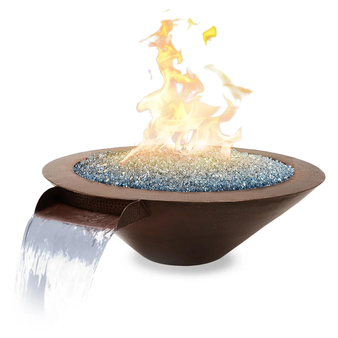 Copper fire pit featuring a waterfall spout, filled with blue fire glass and vibrant flames, perfect as a luxurious and dynamic outdoor centerpiece