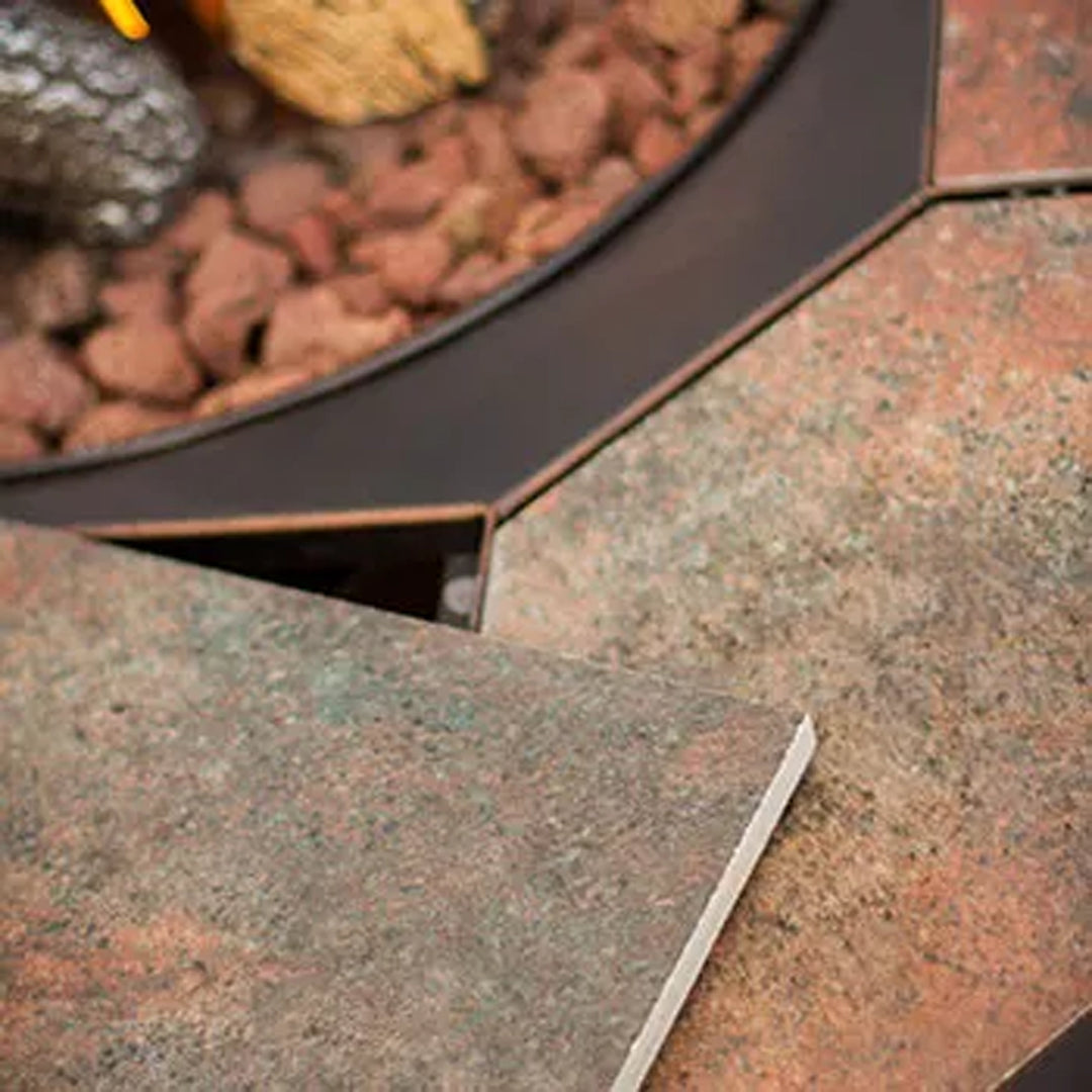 Close-up of a fire pit showing the detailed texture of the stone or tile surface meeting the inner metal ring, with lava rocks inside the pit.